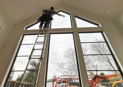 Early Bird Cleaning team member high up a ladder cleaning interior house windows